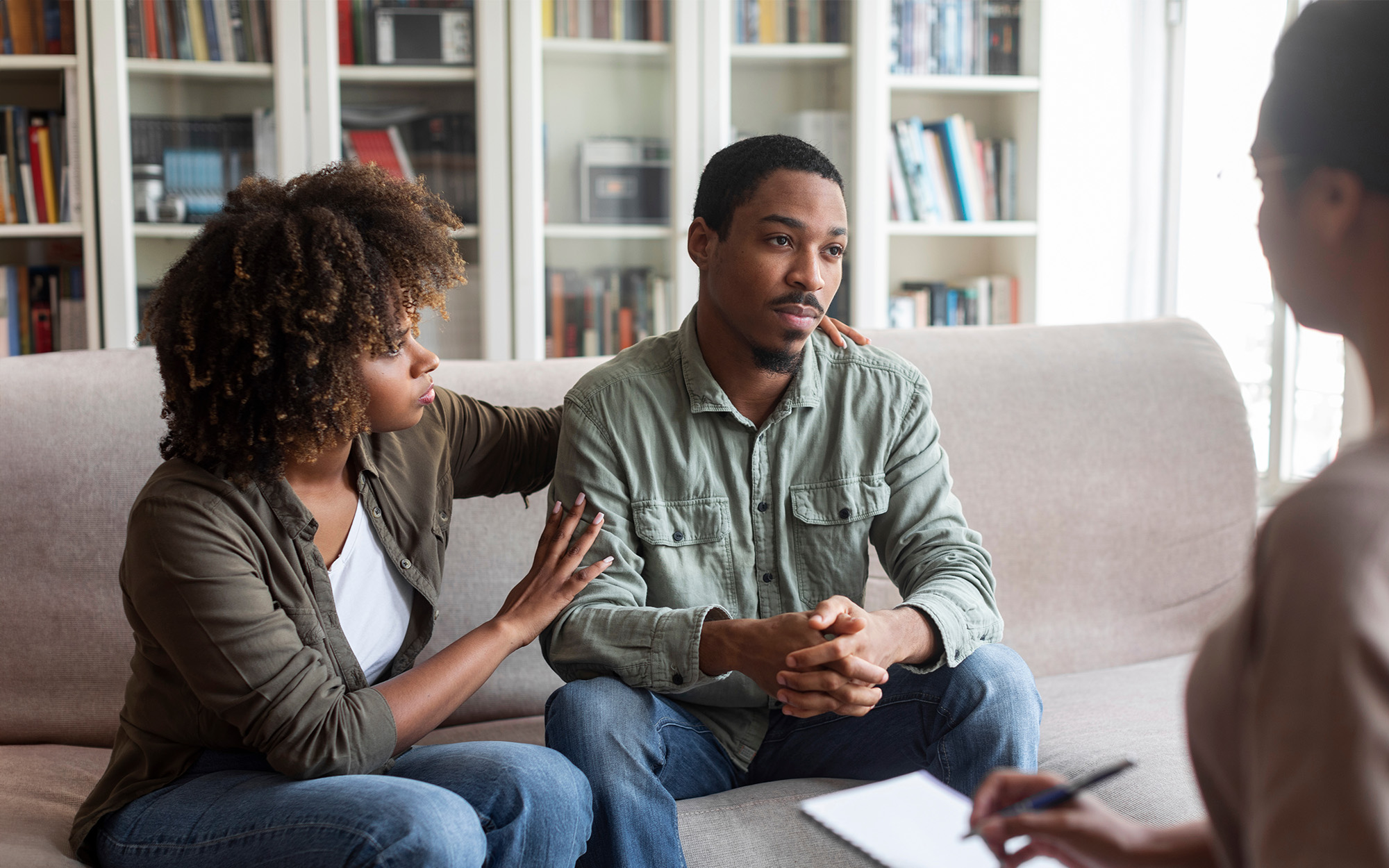 Front view of a man looking seriously at therapist during home appointment